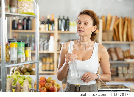Buying mineral water in grocery supermarket - woman chooses tasty and healthy mineral water 138578124
