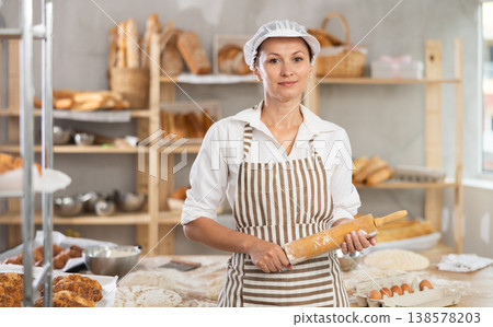 Female baker with rolling pin standing in bakery 138578203