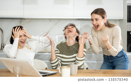 Three happy middle-aged woman expressing joy for winning in the kitchen 138578340