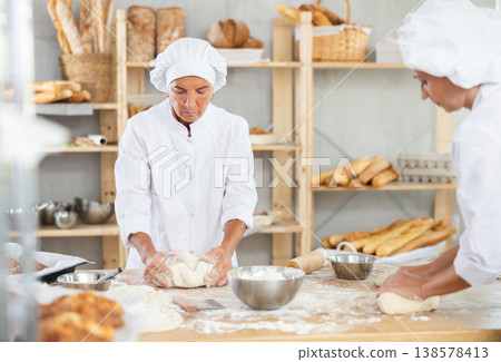 Two women bakers kneading dough in workshop Two women bakers kneading dough in workshop 138578413