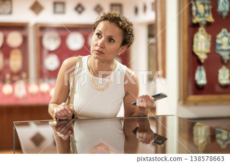 Woman observing artifacts inside glass display case at museum Woman observing artifacts inside glass display case at museum 138578663