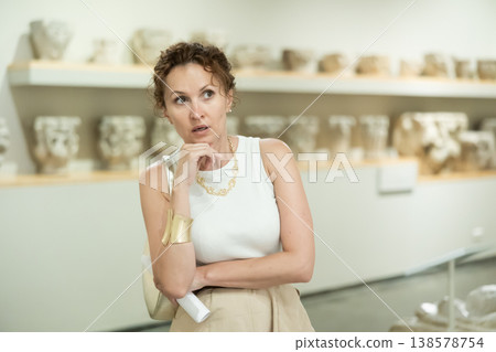 Woman with sheet piece of paper in her hands walks around museum hall 138578754