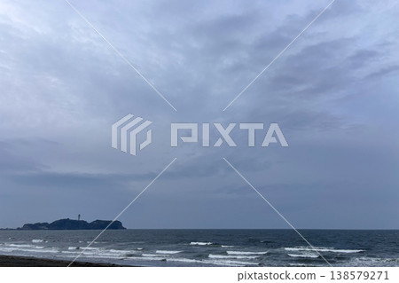 An island with a lighthouse floating on a sea under a cloudy sky, where white waves crash against the shore. An island with a lighthouse floating on a sea under a cloudy sky, where white waves crash against the shore. 138579271