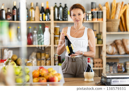 Female salesperson offers to buy bottle of wine in liquor department of grocery supermarket Female salesperson offers to buy bottle of wine in liquor department of grocery supermarket 138579331