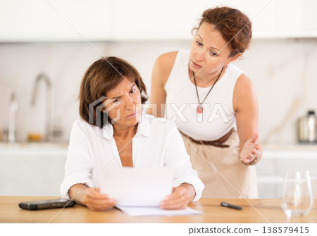 Two women discuss documents, try to solve financial problems Two women discuss documents, try to solve financial problems 138579415