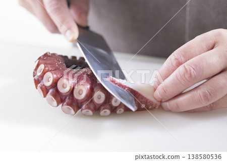A cooking scene showing octopus being cut with a knife. A cooking scene showing octopus being cut with a knife. 138580536