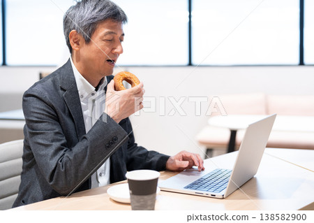 中年商務人士在辦公室休息時吃甜甜圈。 138582900