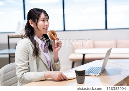 A woman relaxing with coffee and a donut during a break from work. A woman relaxing with coffee and a donut during a break from work. 138582904
