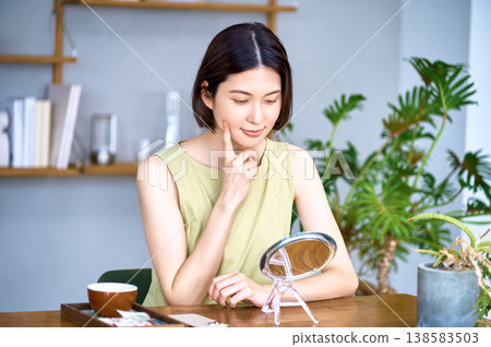 一位非常注重外表的年輕日本女性正在照鏡子檢查自己的皮膚狀況。 一位非常注重外表的年輕日本女性正在照鏡子檢查自己的皮膚狀況。 138583503