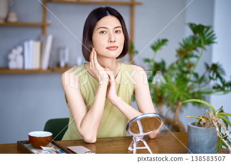 A portrait of a beautiful Japanese woman checking her skin condition while relaxing at home. A portrait of a beautiful Japanese woman checking her skin condition while relaxing at home. 138583507