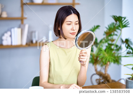 An Asian woman checks the condition of her skin while looking in the mirror. Beauty & Skincare An Asian woman checks the condition of her skin while looking in the mirror. Beauty & Skincare 138583508