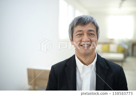 一位六十多歲的男子穿著夾克,在房間裡微笑。 一位六十多歲的男子穿著夾克,在房間裡微笑。 138583773