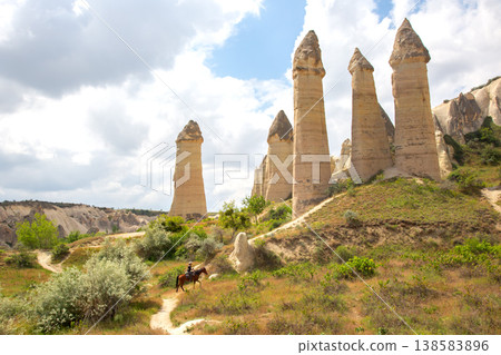 Horse rider near rock formations in Cappadocia, Turkey on a sunny day with clouds in the sky Horse rider near rock formations in Cappadocia, Turkey on a sunny day with clouds in the sky 138583896