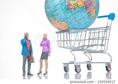 Miniature people use phones while standing by a shopping cart holding a globe in a creative setup Miniature people use phones while standing by a shopping cart holding a globe in a creative setup 138584017