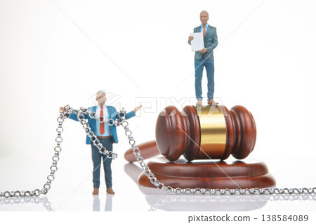 Miniature figurines of people with a gavel and chain in a courtroom setting show a legal theme  138584089