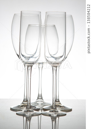 Glasses arranged in a group on a table with a simple background and natural light shining through 138584212