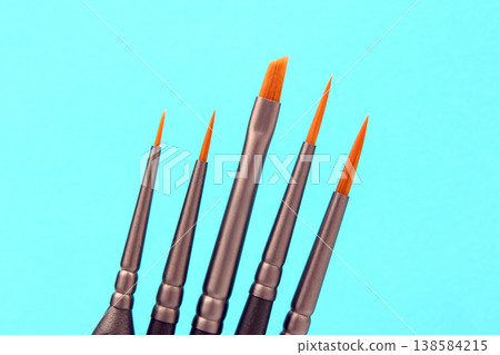 Different sizes of paint brushes on a blue background ready for art projects and creative activities Different sizes of paint brushes on a blue background ready for art projects and creative activities 138584215