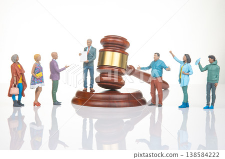 Miniature people gather around a gavel in a courtroom scene with discussions and actions taking Miniature people gather around a gavel in a courtroom scene with discussions and actions taking 138584222