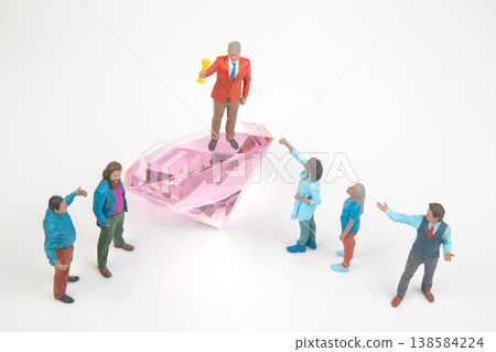 Miniature people celebrate on a giant diamond with one holding a trophy and others cheering Miniature people celebrate on a giant diamond with one holding a trophy and others cheering 138584224