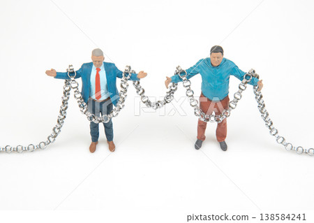 Miniature people holding chains in a playful scene on a white background Miniature people holding chains in a playful scene on a white background 138584241