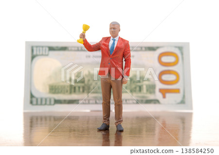 Miniature figurine of a man in a suit holding a trophy in front of a large hundred dollar bill Miniature figurine of a man in a suit holding a trophy in front of a large hundred dollar bill 138584250