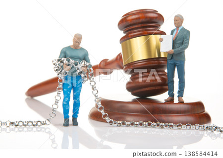 Miniature people near gavel and chains during legal scene with courtroom setting and serious  138584414