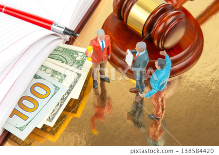 Miniature people discussing legal matters with a judge's gavel and money on a reflective surface Miniature people discussing legal matters with a judge's gavel and money on a reflective surface 138584420