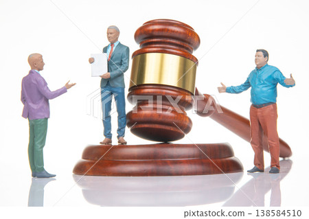 Miniature figurines of people discussing law with a gavel on a table during a courtroom scene 138584510