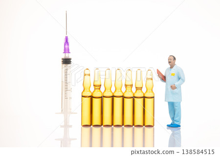 Miniature people performing a science experiment with syringes and vials in a lab setting during Miniature people performing a science experiment with syringes and vials in a lab setting during 138584515