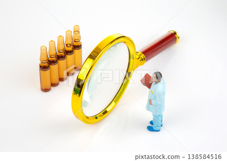 Miniature doctor examines bottles with a magnifying glass in a small setting during the day  138584516