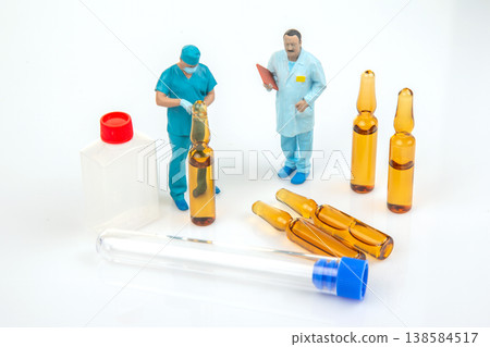Miniature people interact with medical supplies and laboratory tools in a simple setting Miniature people interact with medical supplies and laboratory tools in a simple setting 138584517
