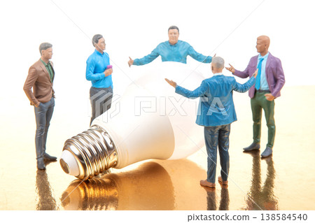 Miniature figurines gather around a light bulb discussing ideas and concepts in a creative setting Miniature figurines gather around a light bulb discussing ideas and concepts in a creative setting 138584540