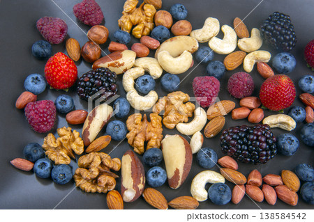 Variety of nuts and berries on a black plate during daytime in a kitchen setting Variety of nuts and berries on a black plate during daytime in a kitchen setting 138584542