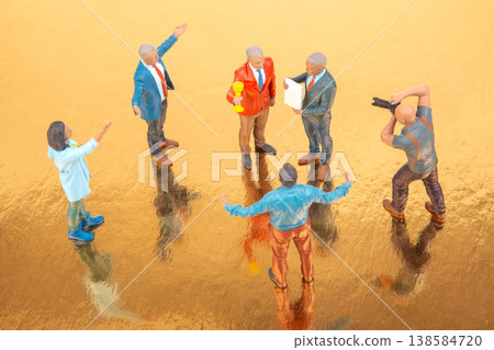 Group of miniature people having a meeting on a shiny surface during the daytime with two figures Group of miniature people having a meeting on a shiny surface during the daytime with two figures 138584720