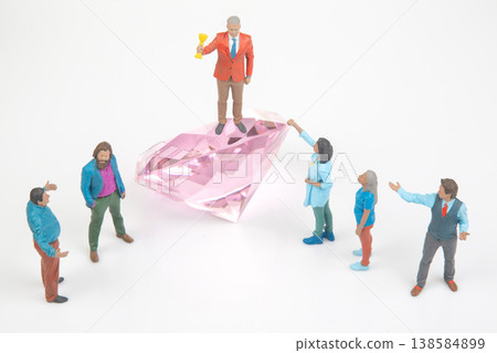 Miniature people gathered around a large diamond with one person celebrating a victory in a creative Miniature people gathered around a large diamond with one person celebrating a victory in a creative 138584899