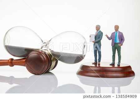 Miniature people holding documents near a gavel and hourglass in a legal setting Miniature people holding documents near a gavel and hourglass in a legal setting 138584909