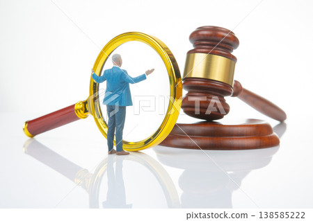 Miniature people examine a large magnifying glass and a gavel in a legal setting Miniature people examine a large magnifying glass and a gavel in a legal setting 138585222