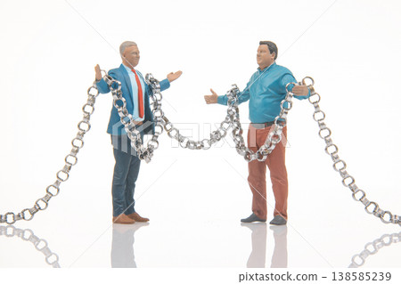 Miniature people holding metal chains in a studio setting during bright daylight 138585239