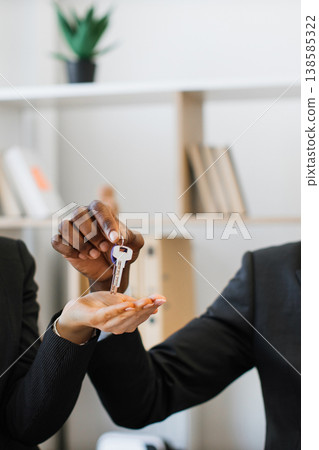 An African American person hands a key to another person, symbolizing a new beginning or successful transaction An African American person hands a key to another person, symbolizing a new beginning or successful transaction 138585322