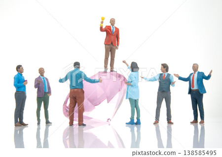 Celebration of success with a group of figures around a large pink gem in an indoor setting Celebration of success with a group of figures around a large pink gem in an indoor setting 138585495