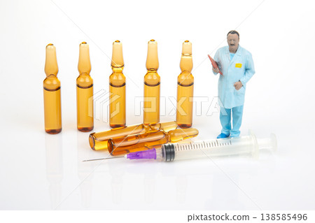Medical supplies on a white surface with a doctor figure holding a clipboard next to syringes  138585496