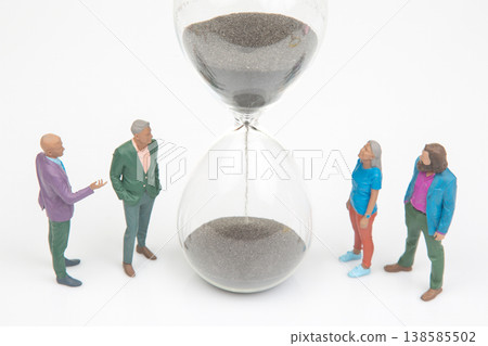 Group of people talking near an hourglass with black sand on white background during a meeting  138585502