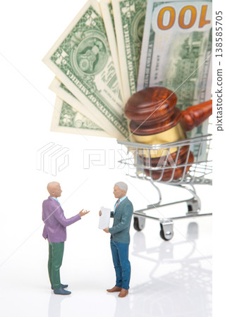 Miniature figurines discussing legal matters in front of money and a gavel in a shopping cart Miniature figurines discussing legal matters in front of money and a gavel in a shopping cart 138585705