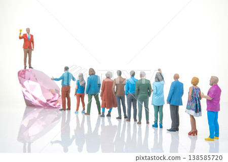 Miniature people celebrate around a large diamond-shaped crystal on a white surface during Miniature people celebrate around a large diamond-shaped crystal on a white surface during 138585720