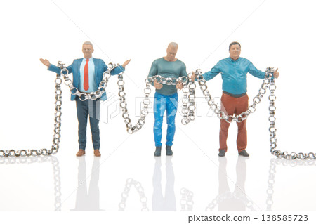 Miniature people hold chains in creative setup showcasing teamwork and cooperation in a unique scene Miniature people hold chains in creative setup showcasing teamwork and cooperation in a unique scene 138585723