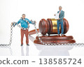 Miniature people with chain near a gavel and a man holding a document in a studio setting during  138585724
