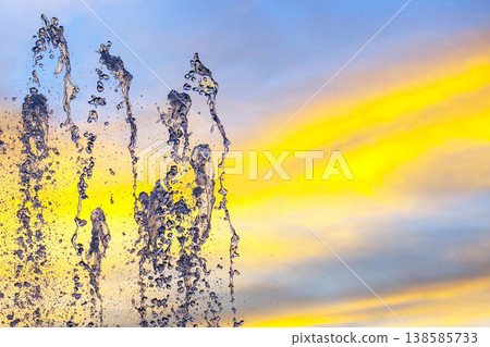 Water fountains splash against a colorful sky during sunset, creating a lively display over Water fountains splash against a colorful sky during sunset, creating a lively display over 138585733