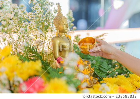 Happy Songkran festival day in Thailand or Thai Happy New Year. hand pouring water on golden Buddha statue with flowers and garland in. Holiday and culture concept Happy Songkran festival day in Thailand or Thai Happy New Year. hand pouring water on golden Buddha statue with flowers and garland in. Holiday and culture concept 138585832