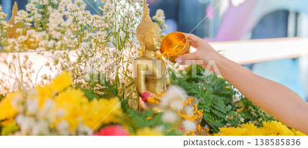 Happy Songkran festival day in Thailand or Thai Happy New Year. hand pouring water on golden Buddha statue with flowers and garland in. Holiday and culture concept Happy Songkran festival day in Thailand or Thai Happy New Year. hand pouring water on golden Buddha statue with flowers and garland in. Holiday and culture concept 138585836