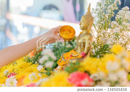 Happy Songkran festival day in Thailand or Thai Happy New Year. hand pouring water on golden Buddha statue with flowers and garland in. Holiday and culture concept Happy Songkran festival day in Thailand or Thai Happy New Year. hand pouring water on golden Buddha statue with flowers and garland in. Holiday and culture concept 138585838